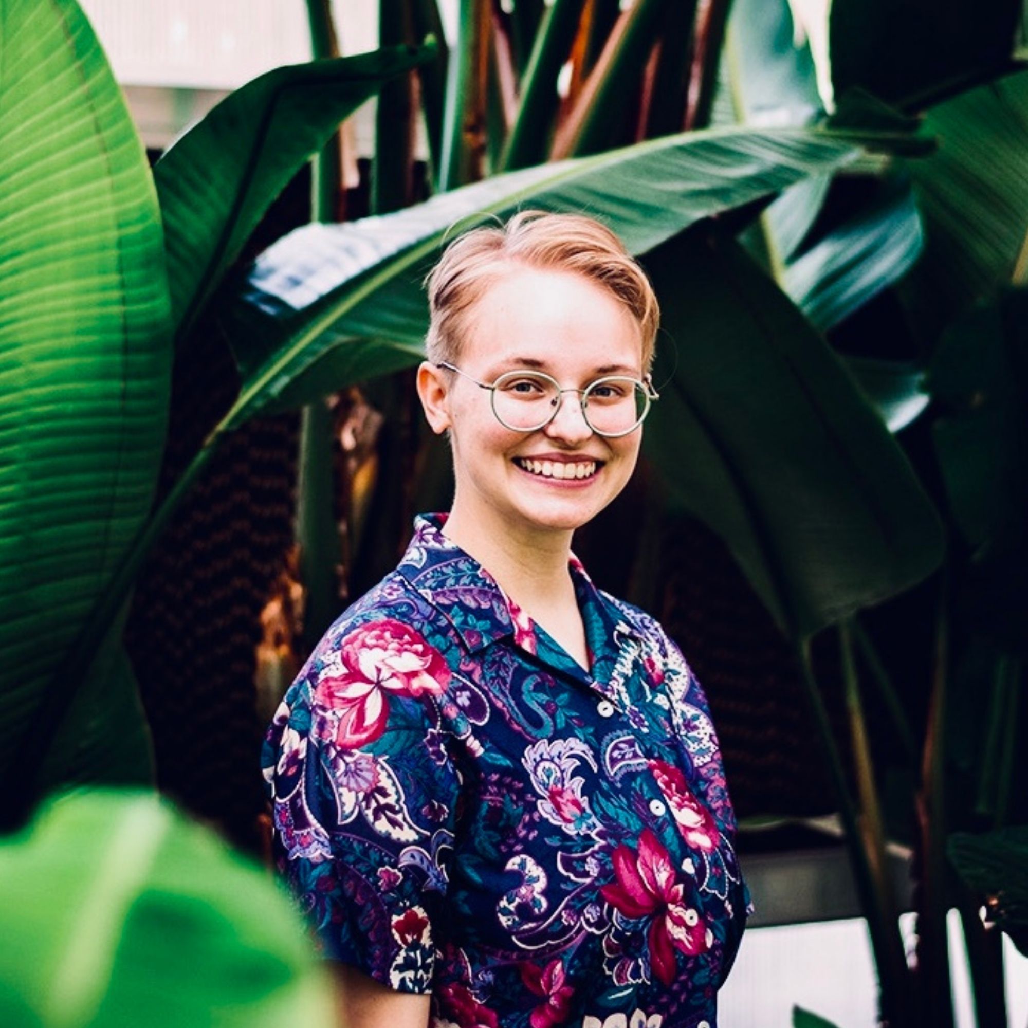 A portrait of Erin Kruse standing in front of banana plant leaves