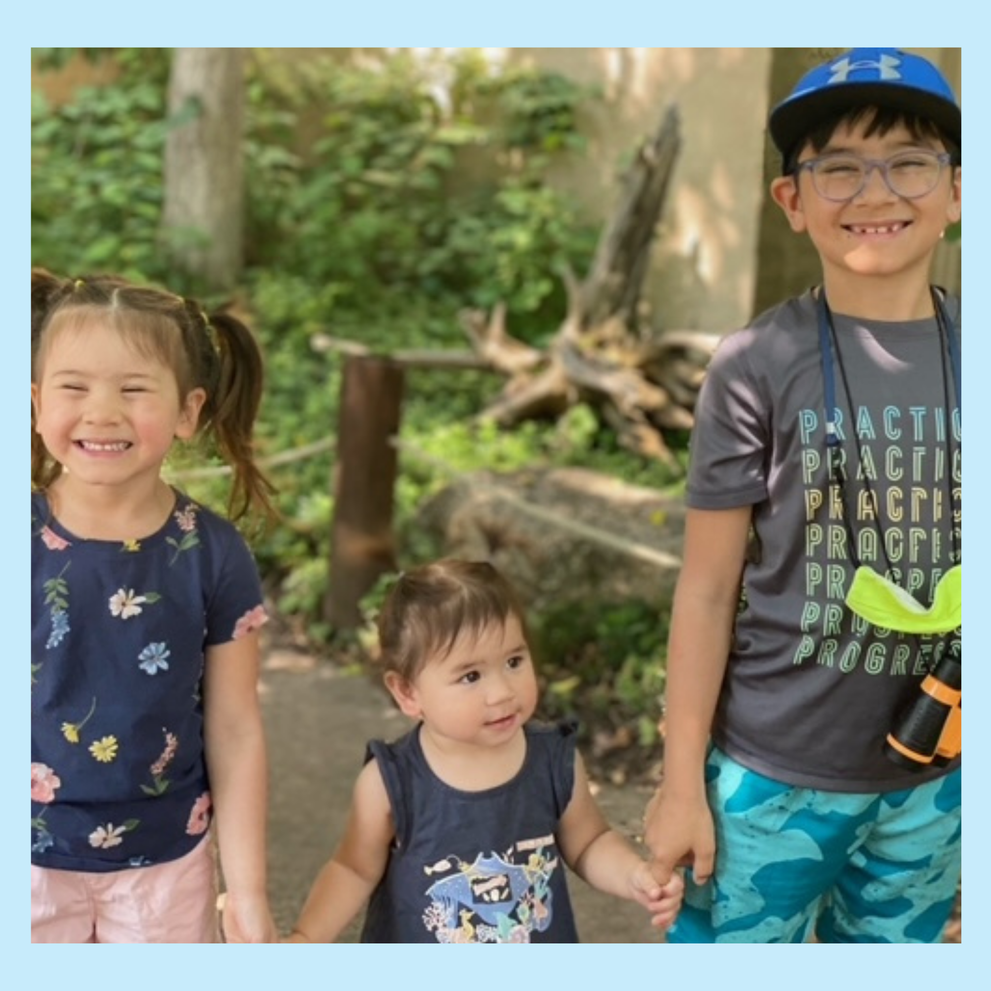 A picture of three young children holding hands in a park.