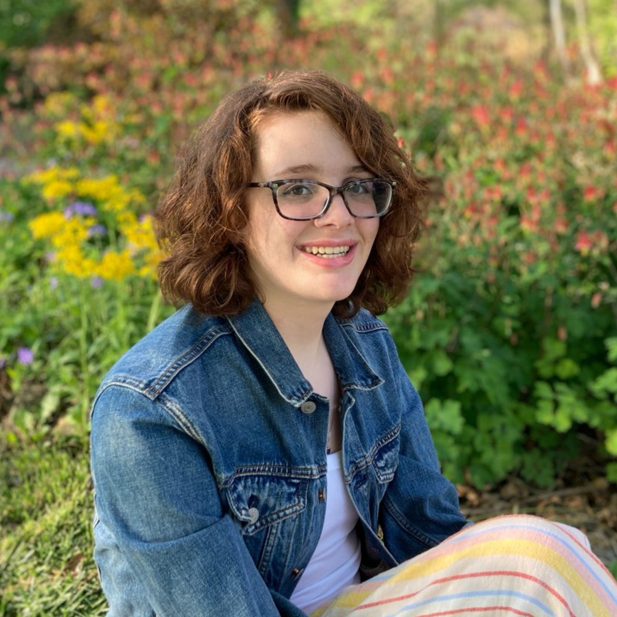 Sarah Dehart Faltico smiling in front of foliage.